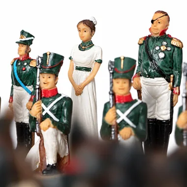 Schaakstukken met soldaten in groen uniform en dame in witte jurk