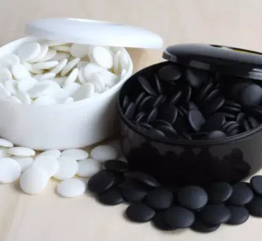 Boîtes de rangement ouvertes contenant les pierres de go noires et blanches
